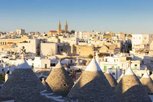 Village of Alberobello illuminated by sun with trulli houses in the foreground Village of Alberobello illuminated by sun with trulli houses in the foreground