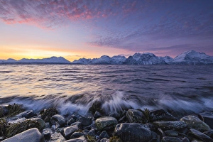 The waves breaking on the stones beach during sunset. Nordmannvik, Kafjord, Lyngen Alps The waves breaking on the stones beach during sunset. Nordmannvik, Kafjord, Lyngen Alps