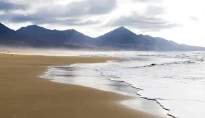 Waves crashing on Cofete Beach with mountains on background, Jandia peninsula Waves crashing on Cofete Beach with mountains on background, Jandia peninsula