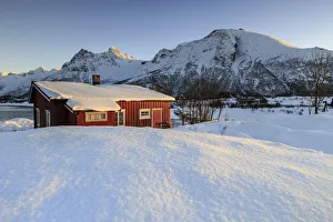 The winter sun illuminates a typical Norwegian red house surrounded by fresh snow The winter sun illuminates a typical Norwegian red house surrounded by fresh snow