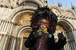 A woman in costume stands in front of the Basilica San Marco in St