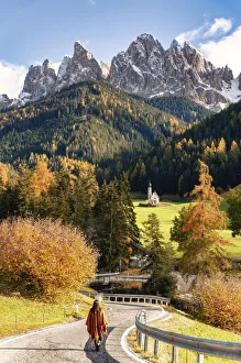 Woman on the road to Santa Maddalena Church. Autumn landscape scenics Woman on the road to Santa Maddalena Church. Autumn landscape scenics