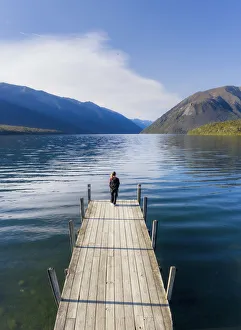 A woman standing on the wooden jetty and enjoying the view of the Rotoiti lake A woman standing on the wooden jetty and enjoying the view of the Rotoiti lake