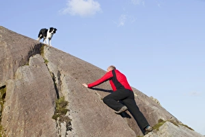 A climber and Border Collie dog on a boulder above Chapel Stile in the Langdale Valley in A climber and Border Collie dog on a boulder above Chapel Stile in the Langdale Valley in