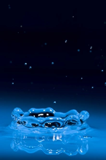 Corona of water splash with many droplets from impact above it. Initial splash was caused by a single drop of water Corona of water splash with many droplets from impact above it. Initial splash was caused by a single drop of water