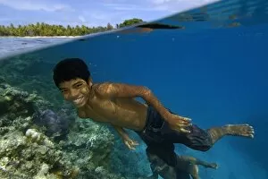 Split Image Collection: Over under image of marshallese boy smiling underwater next to coral reef