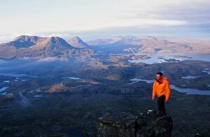 Assynt Gallery: A mountaineer on Suilven summit at Dawn in Scotland UK looking towards Stac Polaidh and Cul Mhor