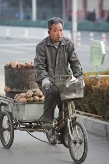 A peasant farmer cycles hius produce to a market in Beijing, China