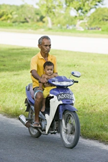 A Tuvaluan man and child on a motorbike on Funafuti atol Tuvalu A Tuvaluan man and child on a motorbike on Funafuti atol Tuvalu