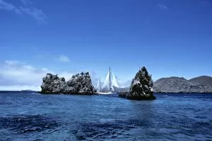 Yacht Aspasia Alpha sailing past Devils Crown, off Punta Cormorant. Floreana Island, Galapagos, Ecuador