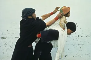 ECUADOR Imbabura Otavalo Indian woman helping another wrap young child in blanket sling ECUADOR Imbabura Otavalo Indian woman helping another wrap young child in blanket sling