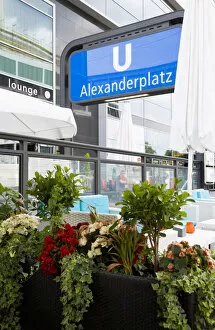 Germany, Berlin, Mitte, cafe tables with seating and planted growing flowers by an