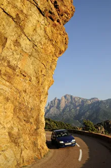 Golden rock face with coastal road & car near Porto Golden rock face with coastal road & car near Porto