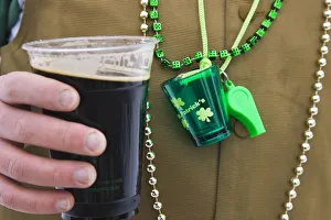 Detail of man wearing various green items whilst drinking pint of stout beer Detail of man wearing various green items whilst drinking pint of stout beer