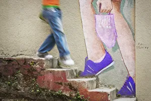 Person walkjing down stone steps past mural of feet walking up stairs Person walkjing down stone steps past mural of feet walking up stairs