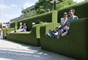 Tourists relax in giant green sofas on the South Bank of the river Thames, London England Tourists relax in giant green sofas on the South Bank of the river Thames, London England