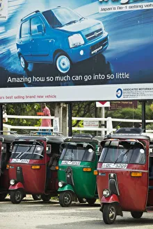 Tuk Tuks parked underneath advertising billboard for Suzuki WagonR Tuk Tuks parked underneath advertising billboard for Suzuki WagonR