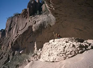 USA New Mexico Bandelier National Monument Visitor climbing ladder amongst caves