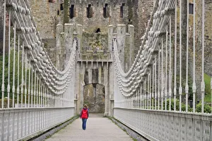 Wales, Conwy, Conwy Suspension Bridge with figure walking towards the walls of Conwy Castle Wales, Conwy, Conwy Suspension Bridge with figure walking towards the walls of Conwy Castle