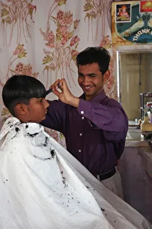Young Indian barber in his barbershop cutting the hair of a boy Young Indian barber in his barbershop cutting the hair of a boy