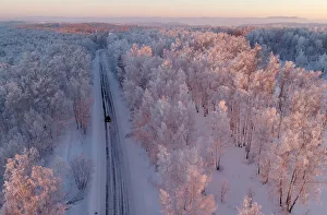 An aerial view shows a car driving along a forest road during sunset in the Siberian An aerial view shows a car driving along a forest road during sunset in the Siberian