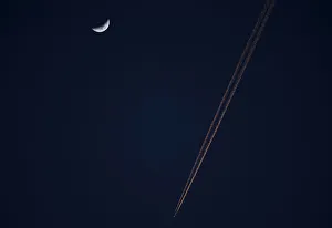 An aeroplane flies past a crescent moon at dusk in Alcala de Henares An aeroplane flies past a crescent moon at dusk in Alcala de Henares