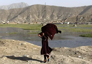 An Afghan girl holds on to her scarf as she walks down a road on a windy day in Kabul An Afghan girl holds on to her scarf as she walks down a road on a windy day in Kabul
