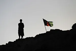 An Afghan policeman stands beside the national flag in southern Afghanistans Helmand An Afghan policeman stands beside the national flag in southern Afghanistans Helmand