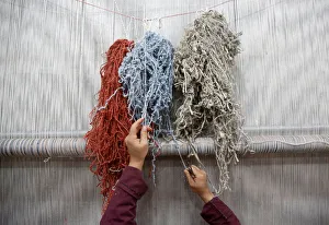 An Afghan woman reaches for a thread while working at the Afghanistan Rug An Afghan woman reaches for a thread while working at the Afghanistan Rug