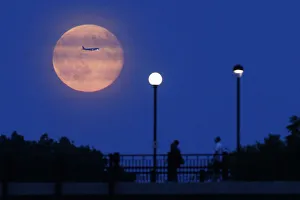 Aircraft passes in front of a Supermoon rising over the Rideau Canal in Ottawa Aircraft passes in front of a Supermoon rising over the Rideau Canal in Ottawa