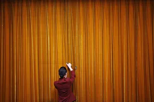An attendant puts clamps on a curtain inside the Great Hall of the People during the An attendant puts clamps on a curtain inside the Great Hall of the People during the