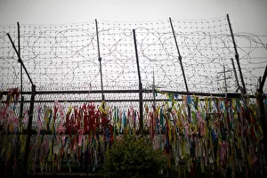 A barbed wire fence is decorated with ribbons bearing messages wishing for unification of A barbed wire fence is decorated with ribbons bearing messages wishing for unification of
