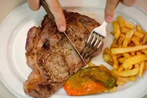 A beef steak is cut at the Taberna del Gijon restaurant in Madrid A beef steak is cut at the Taberna del Gijon restaurant in Madrid