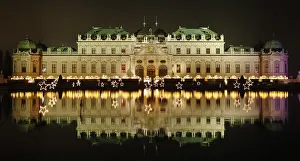 Belvedere palace is reflected in a pond behind the lights of an advent market in Vienna Belvedere palace is reflected in a pond behind the lights of an advent market in Vienna