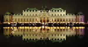 Images Dated 16th December 2014: Belvedere palace is reflected in a pond behind the lights of an advent market in Vienna