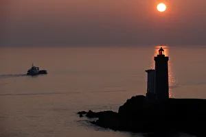A boat makes his way behind the Phare du Petit Minou as the sun sets over the Atlantic A boat makes his way behind the Phare du Petit Minou as the sun sets over the Atlantic