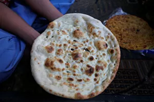 A boy holds for camera a naan after it was cooked in an oven at a shop in Karachi