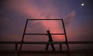 A boy walks past a structure being set up on a bridge to block the view of those passing A boy walks past a structure being set up on a bridge to block the view of those passing