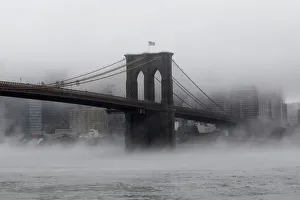 The Brooklyn Bridge is seen partially in fog from in front of the Manhattan skyline in The Brooklyn Bridge is seen partially in fog from in front of the Manhattan skyline in