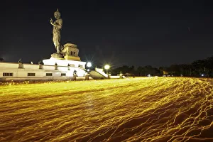 Buddhists holding candles encircle a large Buddha statue during Makha Bucha Day at Buddhists holding candles encircle a large Buddha statue during Makha Bucha Day at