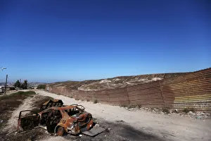 Tijuana Gallery: A burnt car is seen next to a section of the wall separating Mexico and the United States