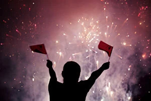 Images Dated 30th September 2005: A Chinese girl waves national flags as she watches fireworks at the celebration of