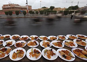 Commuters travel past plates of food, placed for passers-by to break their fast during Commuters travel past plates of food, placed for passers-by to break their fast during
