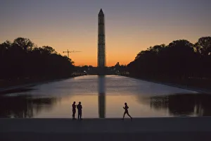 A couple and a jogger pass by the Lincoln Memorial Reflecting Pool before sunrise A couple and a jogger pass by the Lincoln Memorial Reflecting Pool before sunrise