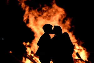 A couple kiss next to of the bonfire on the Poniente beach celebrating the summer A couple kiss next to of the bonfire on the Poniente beach celebrating the summer