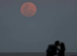 A couple kisses as a supermoon rises in the sky over the Rio de La Plata in Buenos Aires A couple kisses as a supermoon rises in the sky over the Rio de La Plata in Buenos Aires