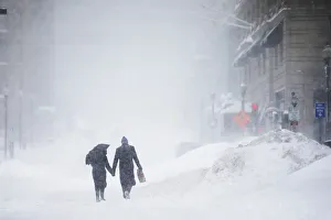 Couple walks hand-in-hand through the snow in the Back Bay during a winter blizzard in Couple walks hand-in-hand through the snow in the Back Bay during a winter blizzard in