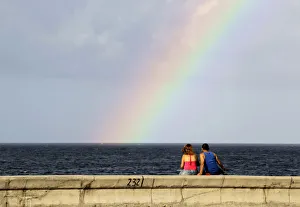 Images Dated 29th August 2010: A couple watches a rainbow from Havanas seafront boulevard El Malecon