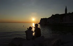 A couple watches the sunset during the first day of summer in the Adriatic town of Rovinj A couple watches the sunset during the first day of summer in the Adriatic town of Rovinj
