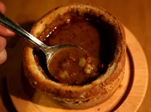 A customer eats a goulash soup from a bread bowl in a restaurant in Prague A customer eats a goulash soup from a bread bowl in a restaurant in Prague